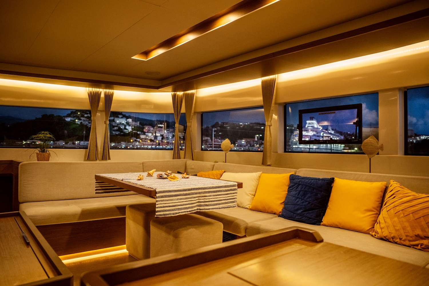 Yacht saloon at night with warm lighting and city view